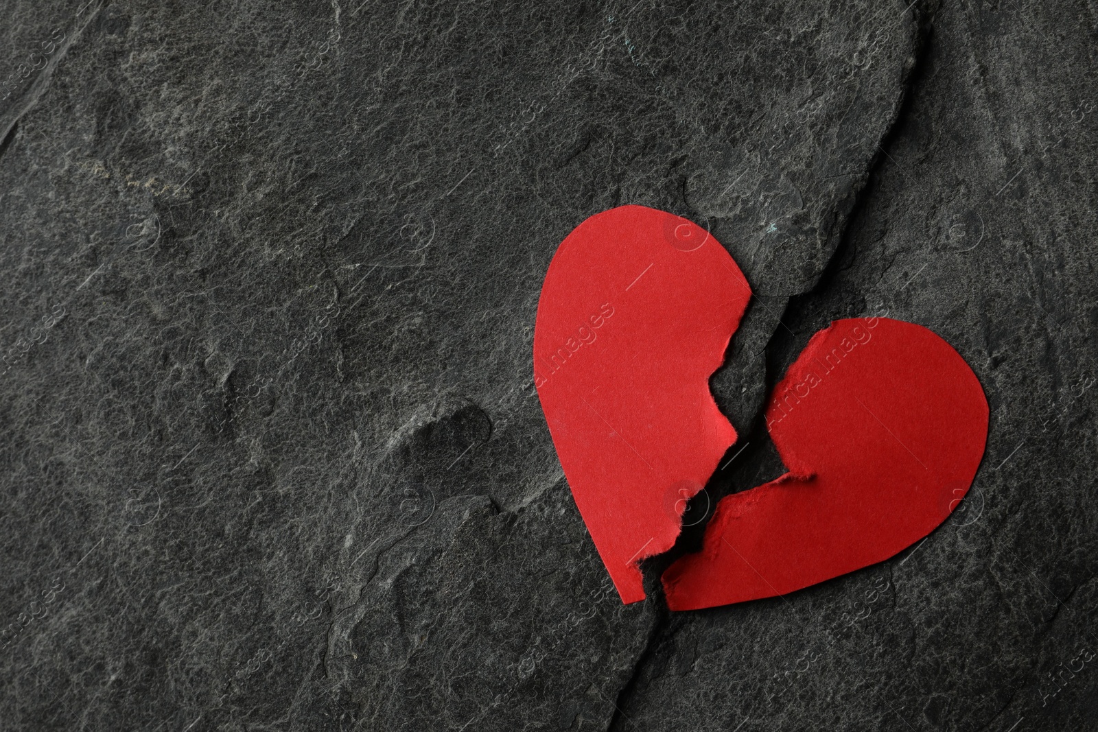 Photo of Broken heart. Halves of torn red paper heart on dark grey table, top view. Space for text