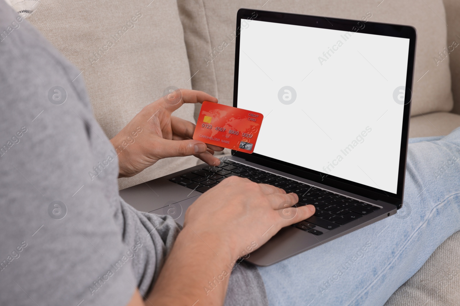 Photo of Man with credit card using laptop for online shopping on sofa, closeup