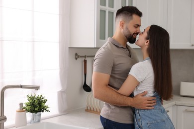 Affectionate couple hugging in kitchen. Space for text