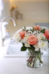 Photo of Vase with beautiful flowers on countertop in kitchen. Interior design