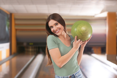 Photo of Young woman with ball in bowling club