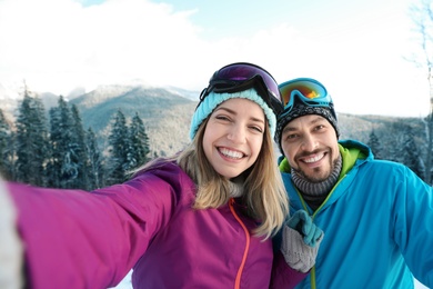 Photo of Happy couple taking selfie during winter vacation in mountains