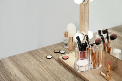 Photo of Makeup cosmetic products with tools in organizer on dressing table. Space for text