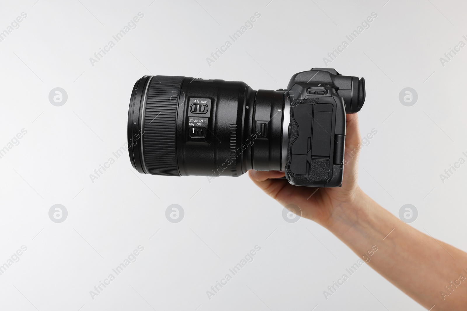 Photo of Photographer with camera on light grey background, closeup