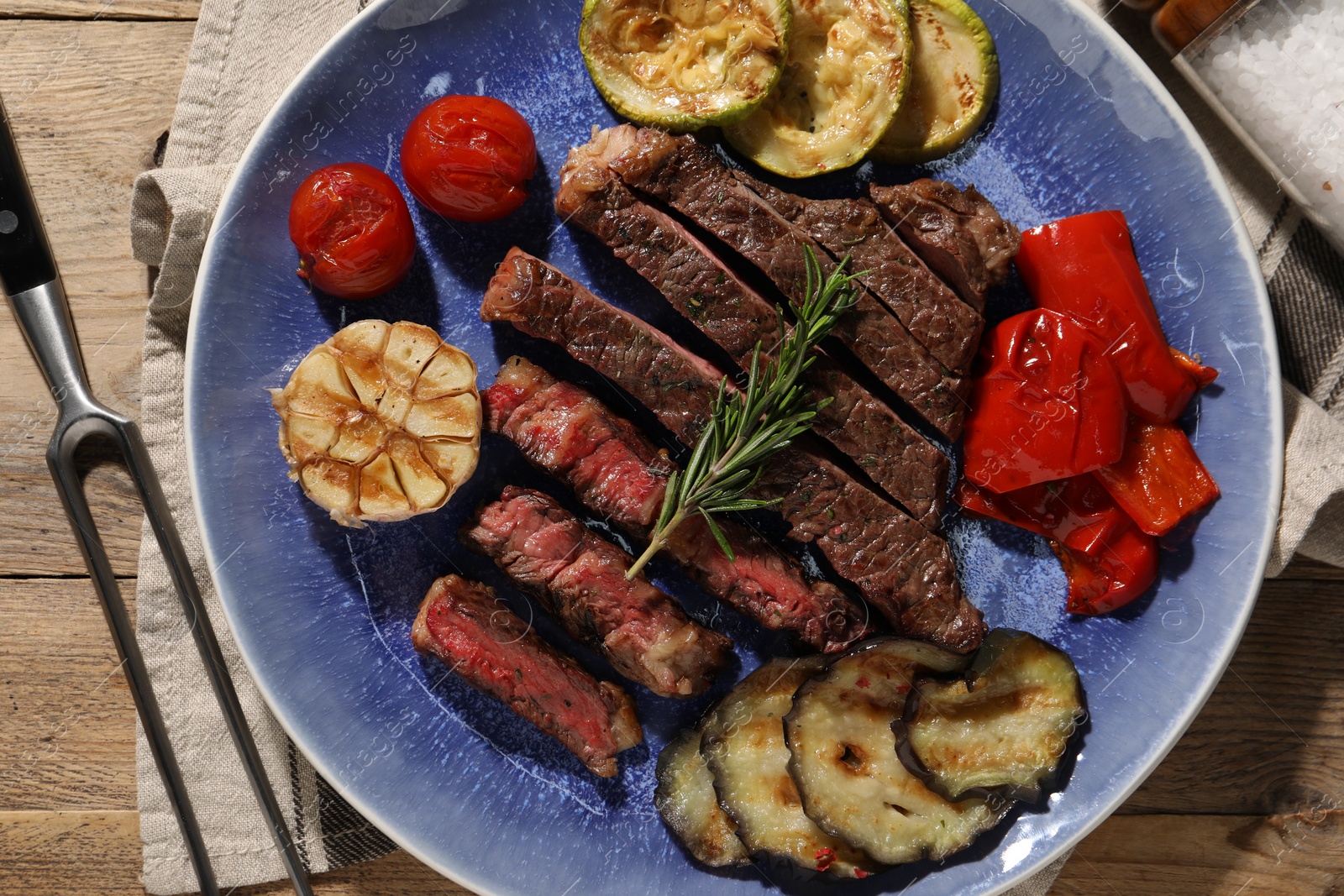 Photo of Delicious grilled beef steak with vegetables and spices on table, top view