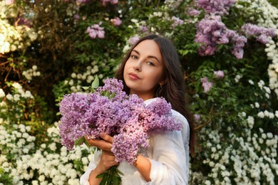 Attractive young woman with lilac flowers outdoors