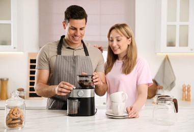 Photo of Lovely couple together in kitchen, man using electric coffee grinder