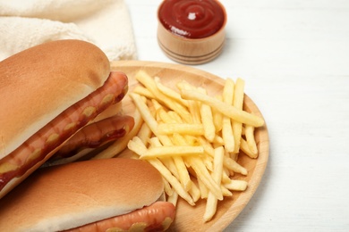 Photo of Hot dogs, french fries and sauce on table, closeup