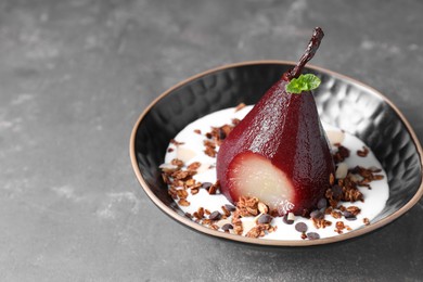 Tasty red wine poached pear with muesli and yoghurt in bowl on grey table, closeup. Space for text