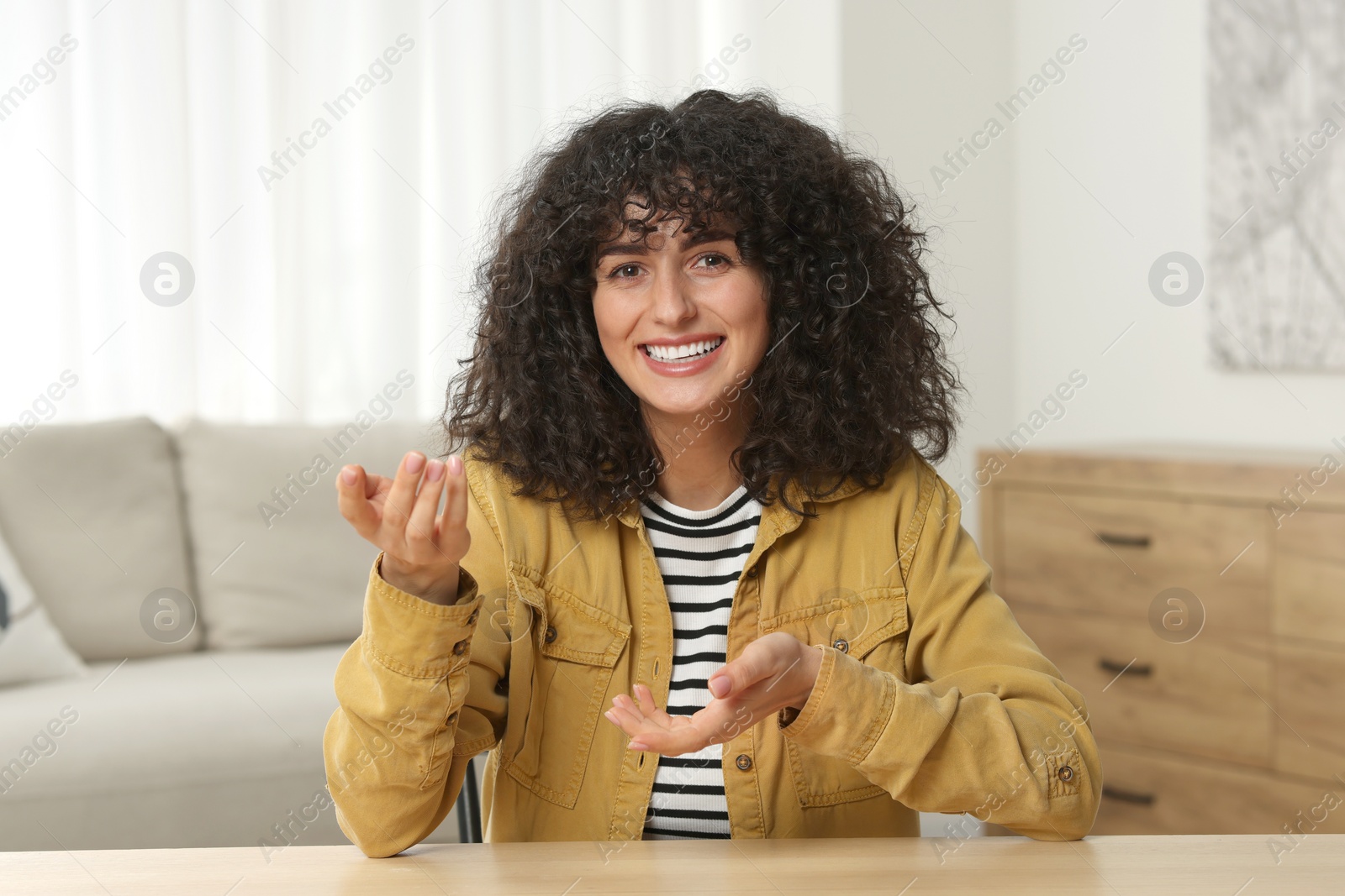 Photo of Happy woman sitting at wooden table in room