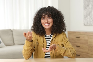 Happy woman sitting at wooden table in room