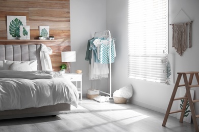 Photo of Stylish bedroom interior with clothing rack and large window