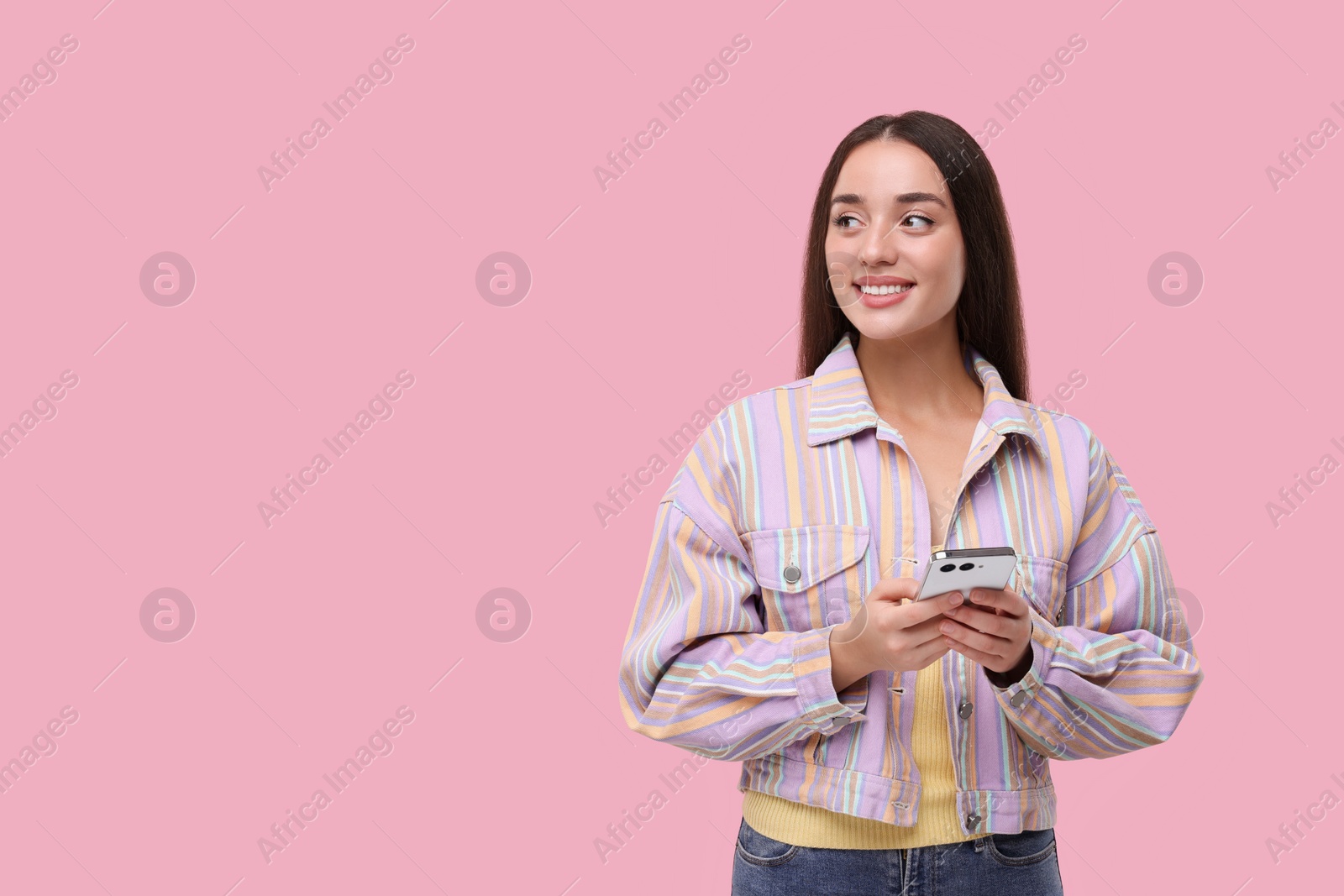 Photo of Happy woman sending message via smartphone on pink background, space for text