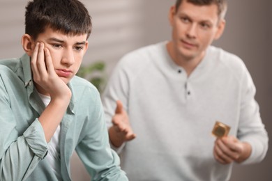 Photo of Father talking with his teenage son about contraception at home. Sex education concept