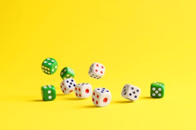 Photo of Many color game dices falling on yellow background