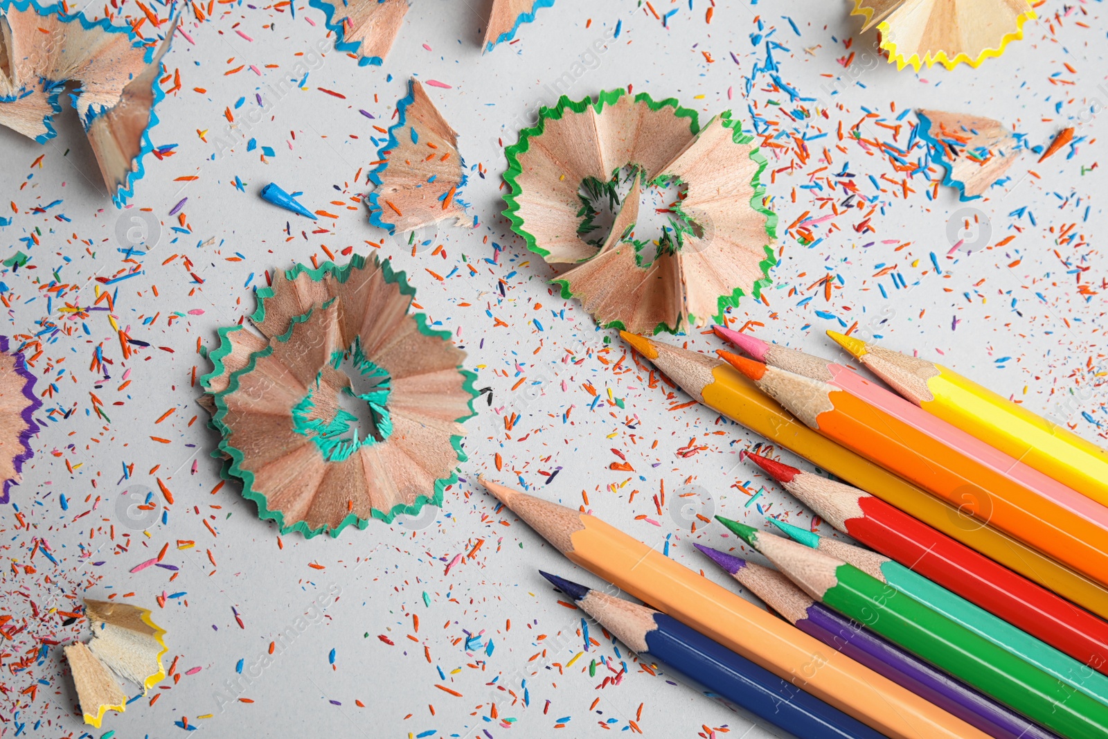 Photo of Color pencils and shavings on grey background, top view