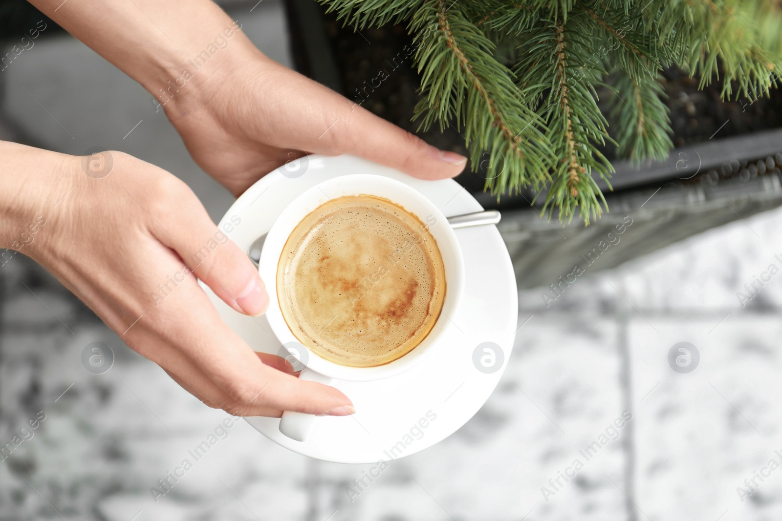 Photo of Young woman with cup of delicious coffee on blurred background