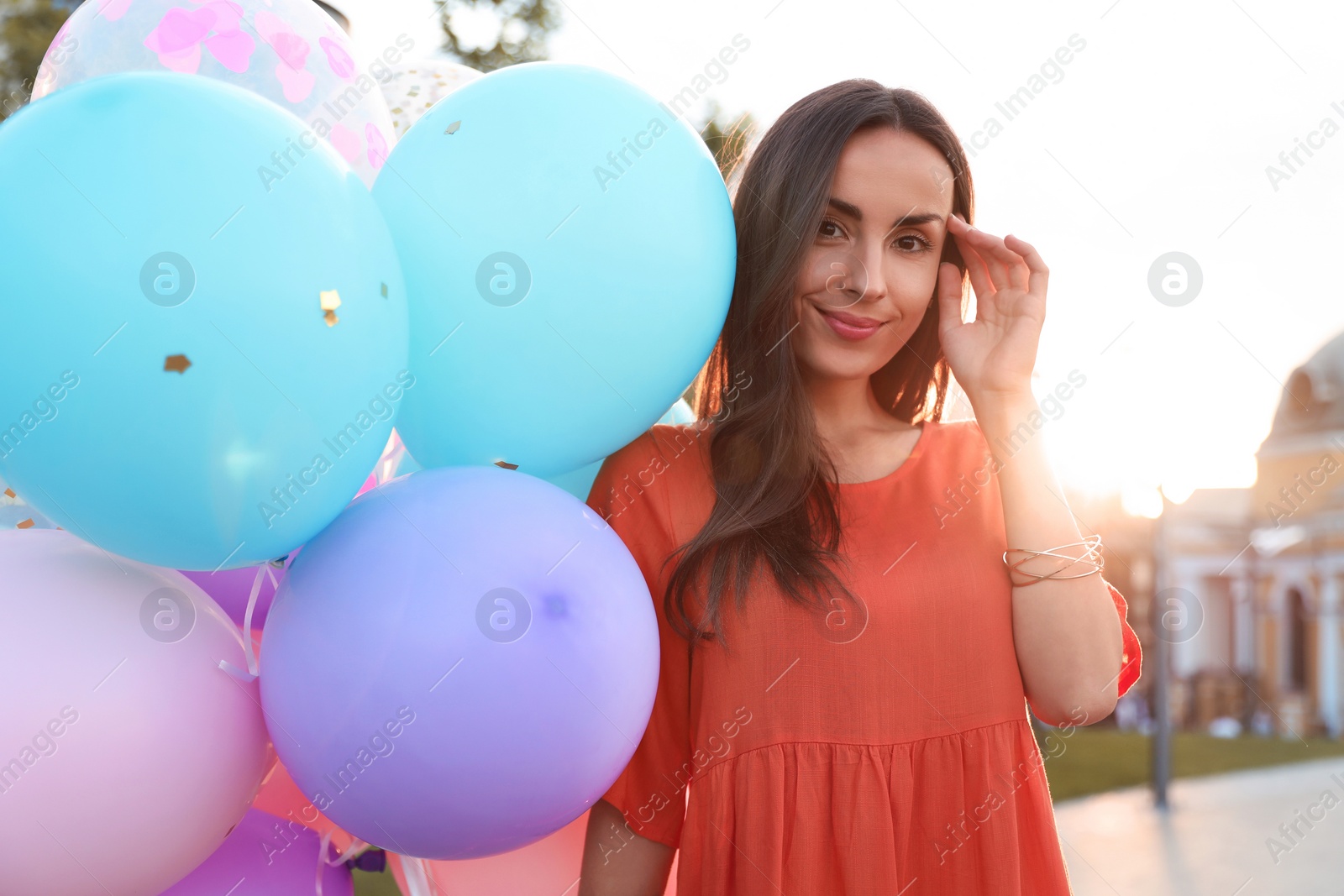 Photo of Cheerful young woman with color balloons outdoors on sunny day