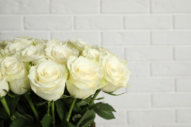 Photo of Luxury bouquet of fresh roses near white brick wall, closeup