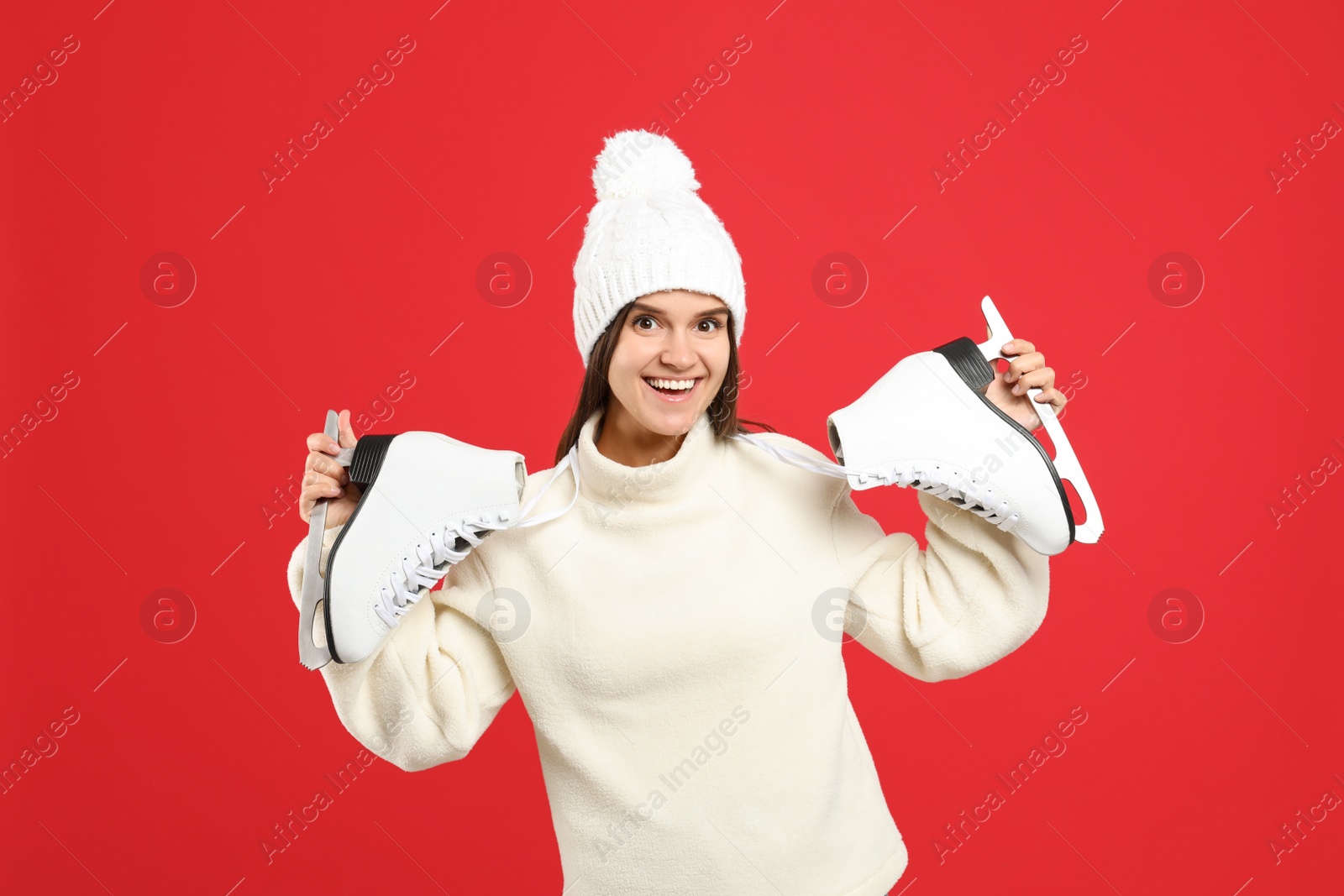 Photo of Happy woman with ice skates on red background