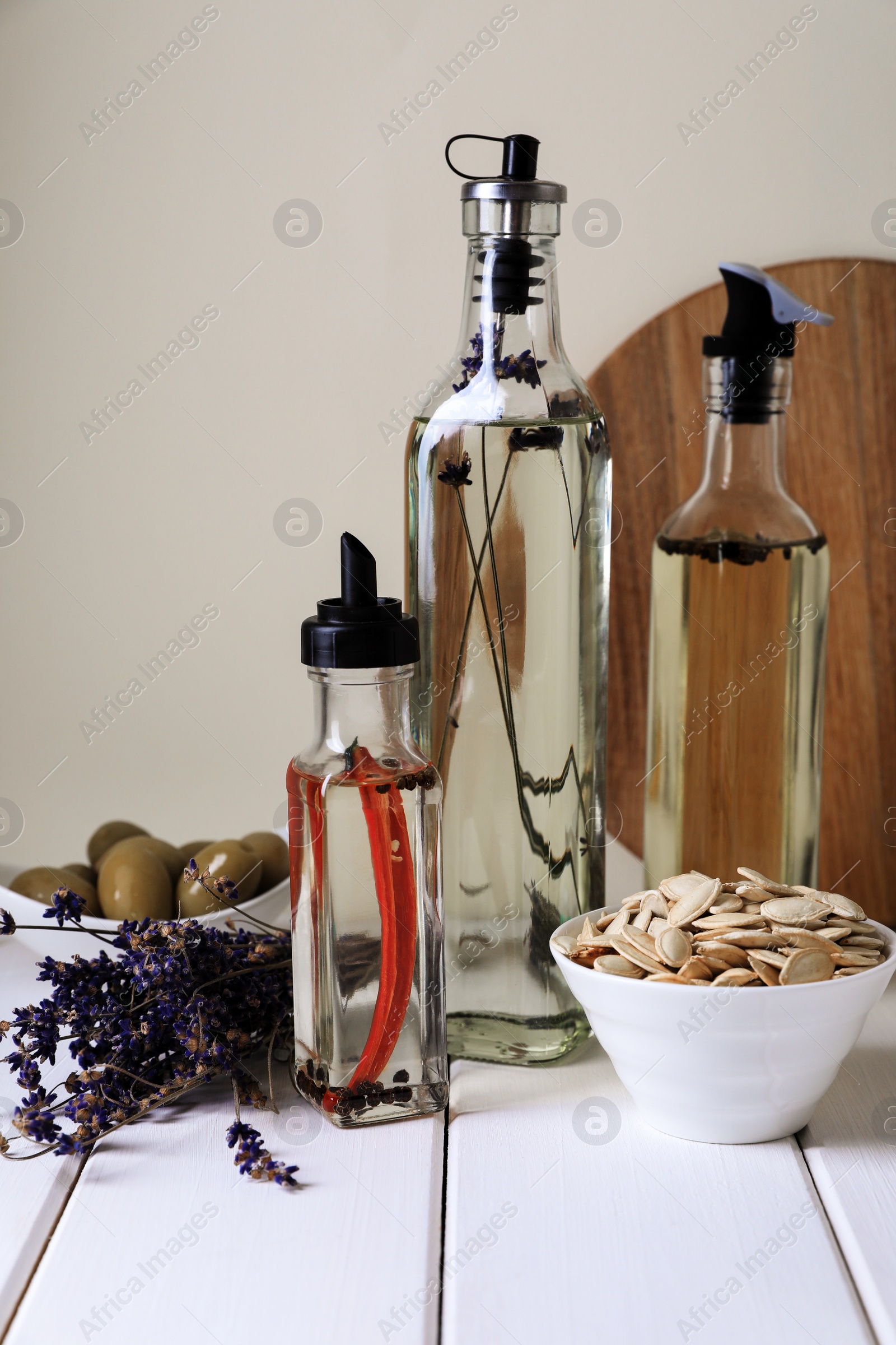 Photo of Different cooking oils and ingredients on white wooden table against light background