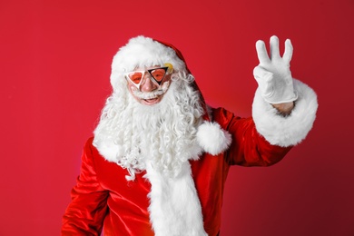 Photo of Authentic Santa Claus wearing sunglasses on color background