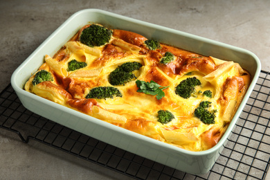 Photo of Tasty broccoli casserole in baking dish on cooling rack