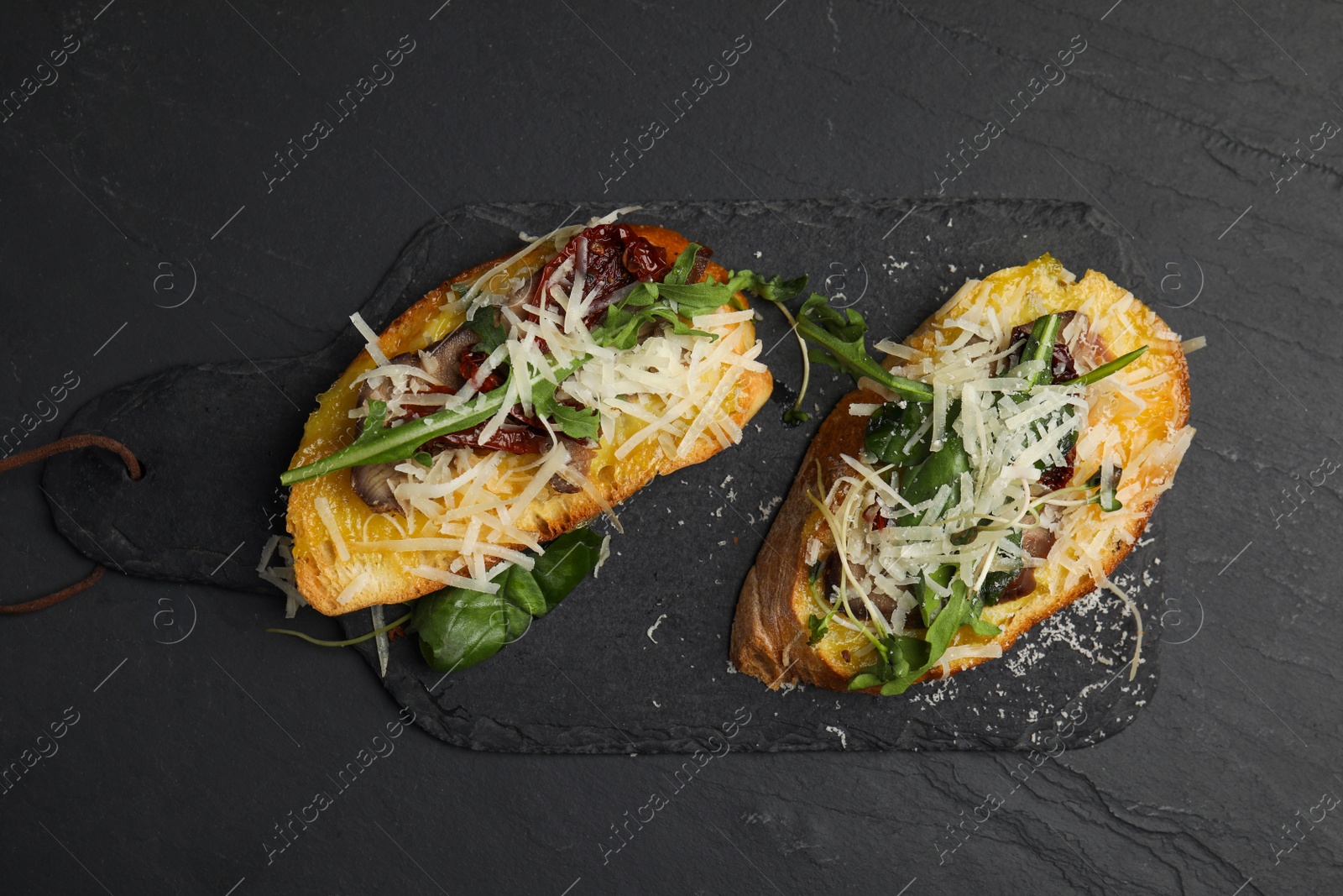 Photo of Delicious bruschettas with beef and cheese on black table, flat lay