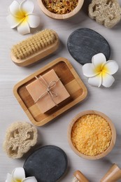 Photo of Flat lay composition with different spa products and flowers on light wooden table