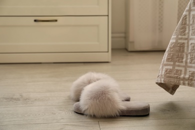 Grey fuzzy slippers on floor in room