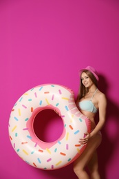 Photo of Beautiful young woman in bikini with inflatable ring against color background