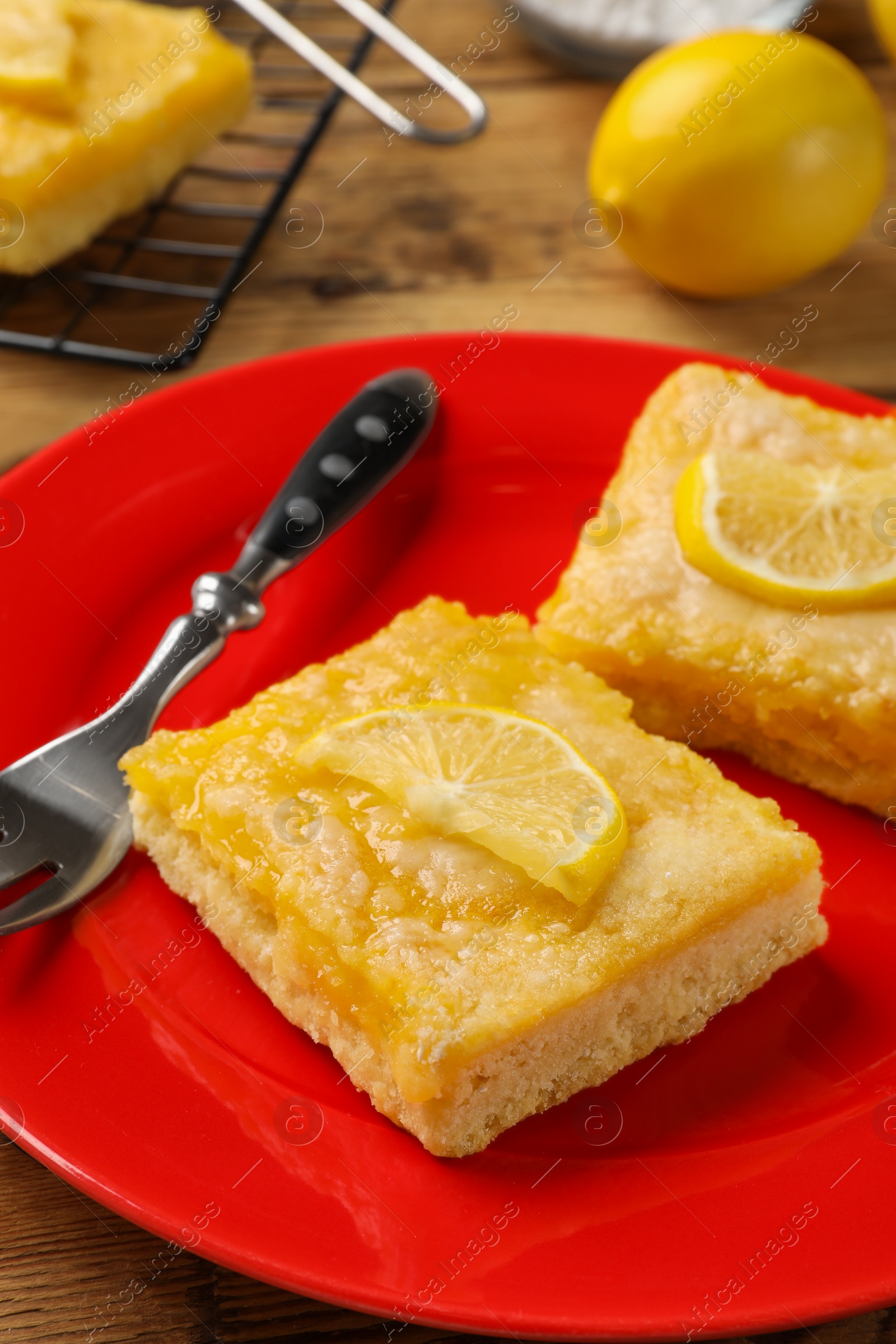 Photo of Tasty lemon bars and fork on table, closeup