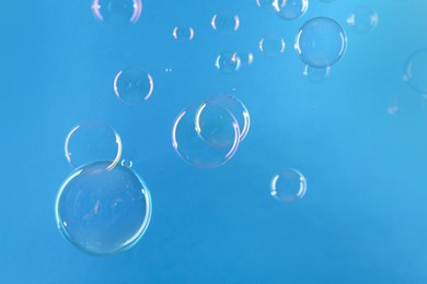 Beautiful transparent soap bubbles on light blue background