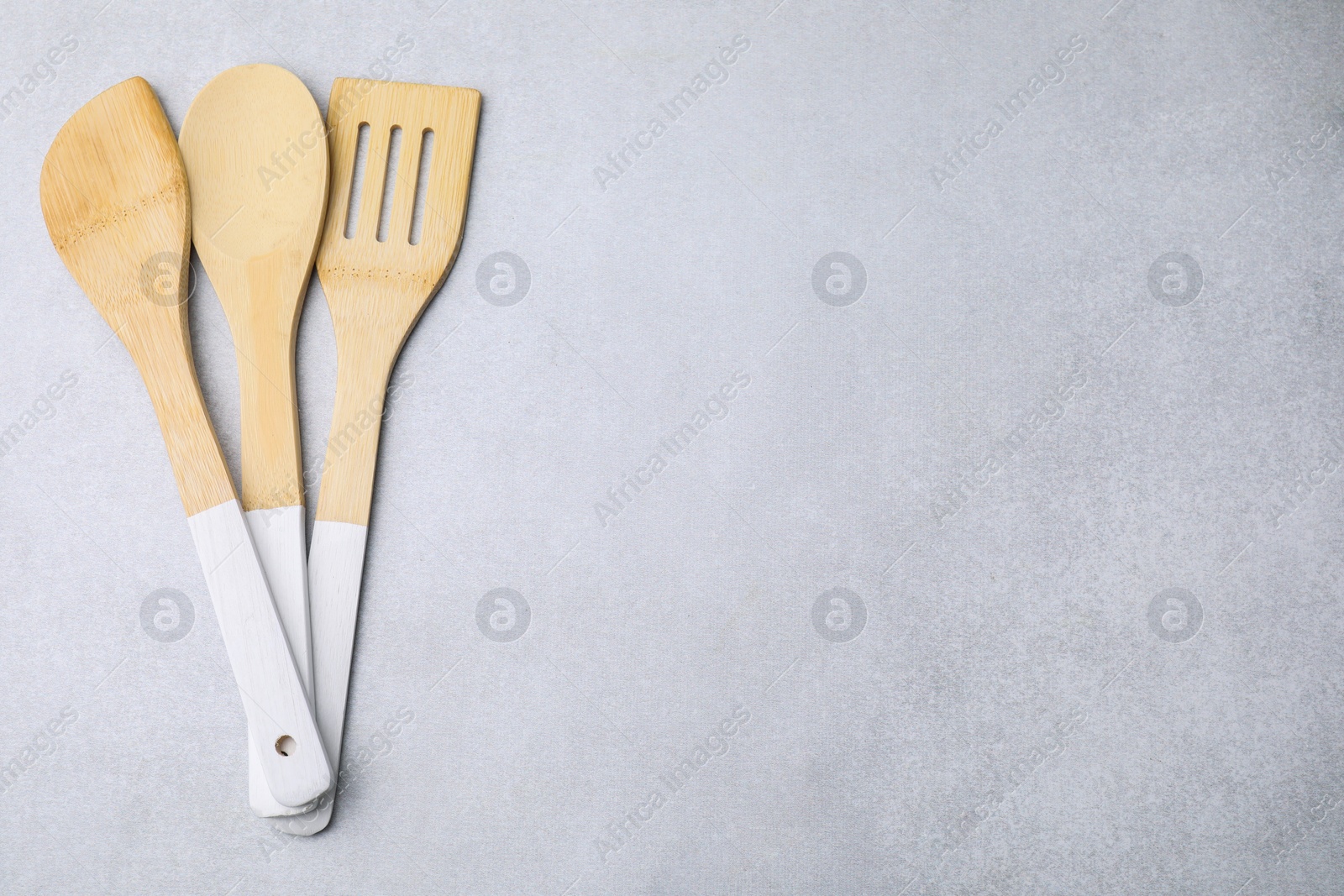 Photo of Set of wooden cooking utensils on light grey table, flat lay. Space for text