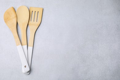 Photo of Set of wooden cooking utensils on light grey table, flat lay. Space for text