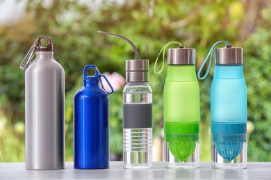 Photo of Sports water bottles on table against blurred background