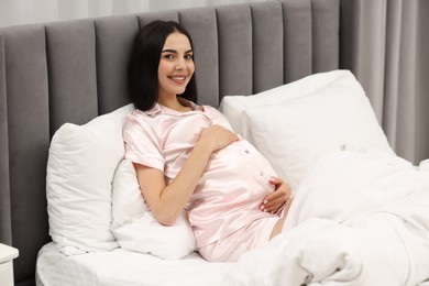 Happy pregnant woman in bed at home