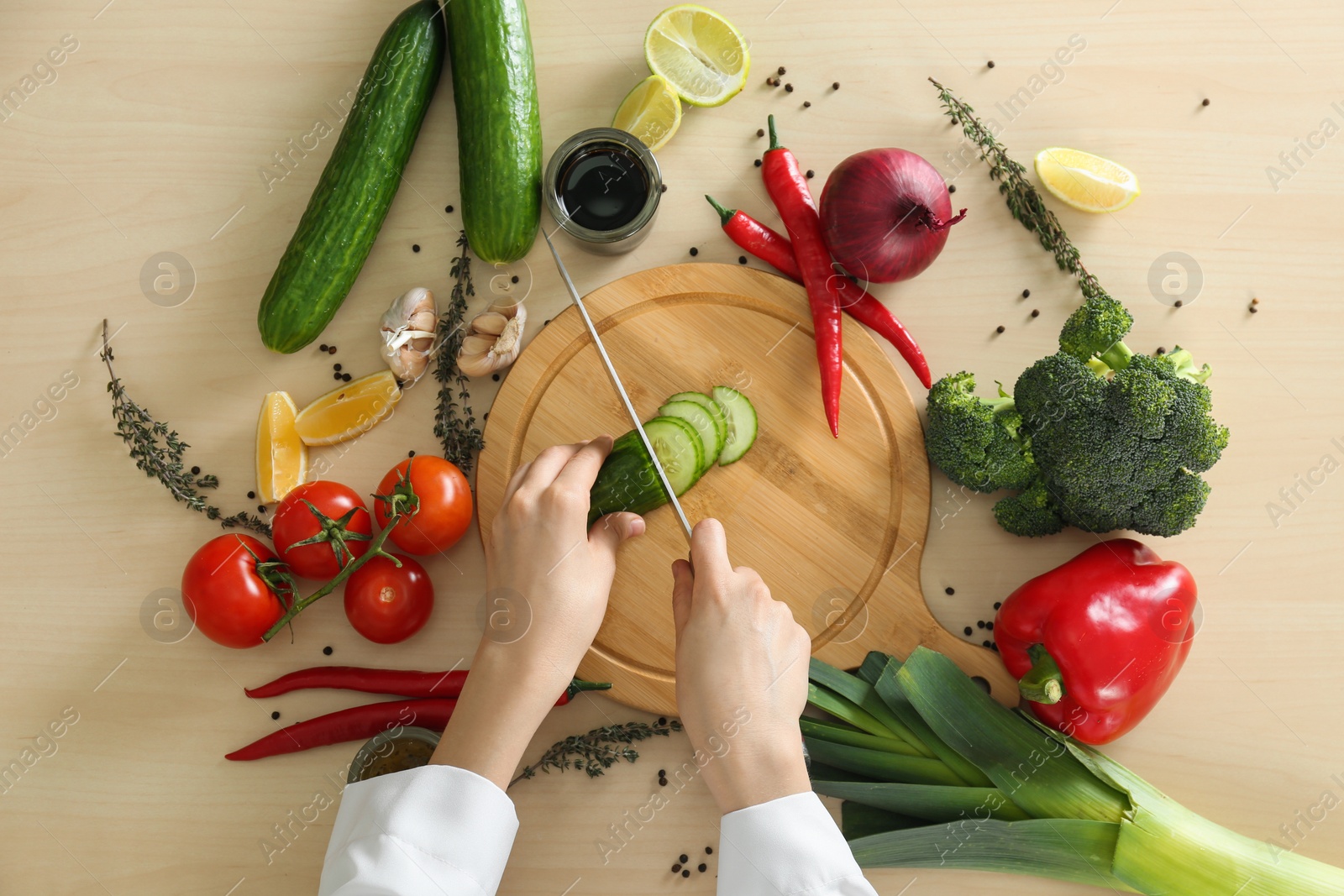 Photo of Woman cooking food at wooden kitchen table, flat lay