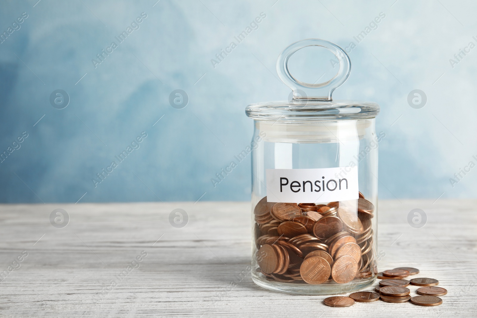 Photo of Glass jar with label PENSION and coins on white wooden table. Space for text