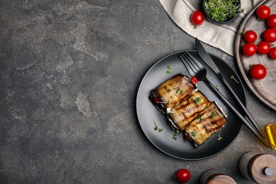 Photo of Delicious baked eggplant rolls served on grey table, flat lay. Space for text