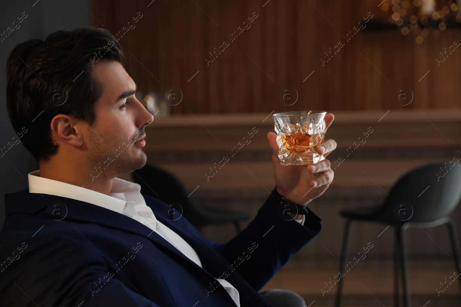 Photo of Young man with glass of whiskey in bar