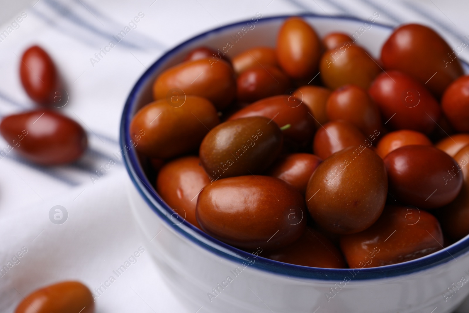 Photo of Fresh Ziziphus jujuba fruits in bowl on table, closeup