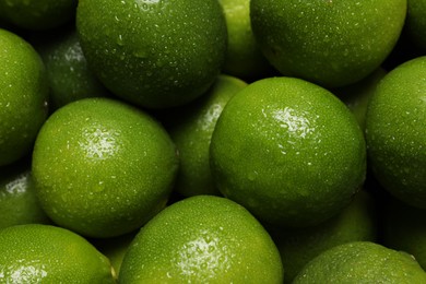 Photo of Fresh ripe limes with water drops as background, closeup