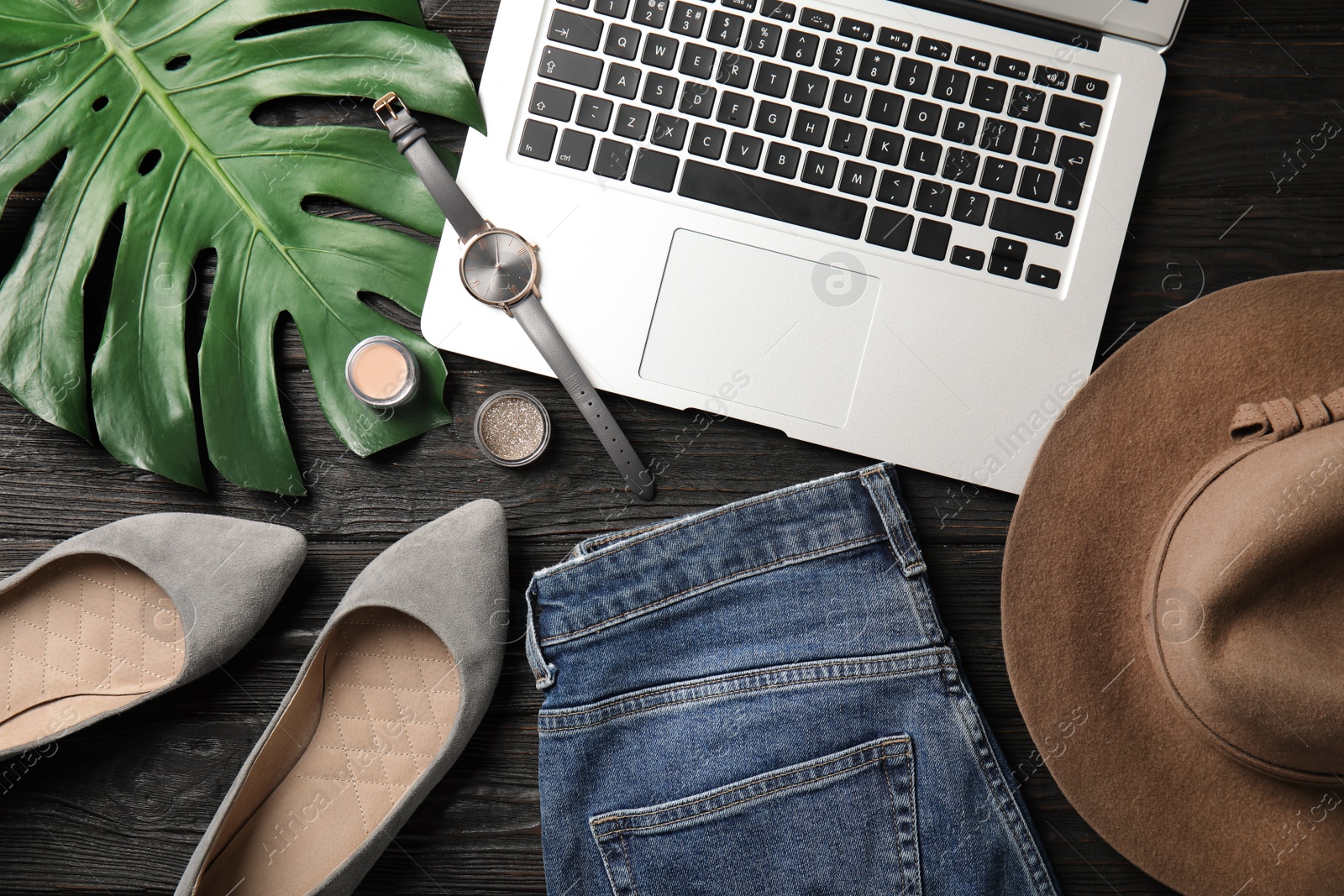 Photo of Flat lay composition with laptop and stylish clothes on wooden table. Blogger's workplace