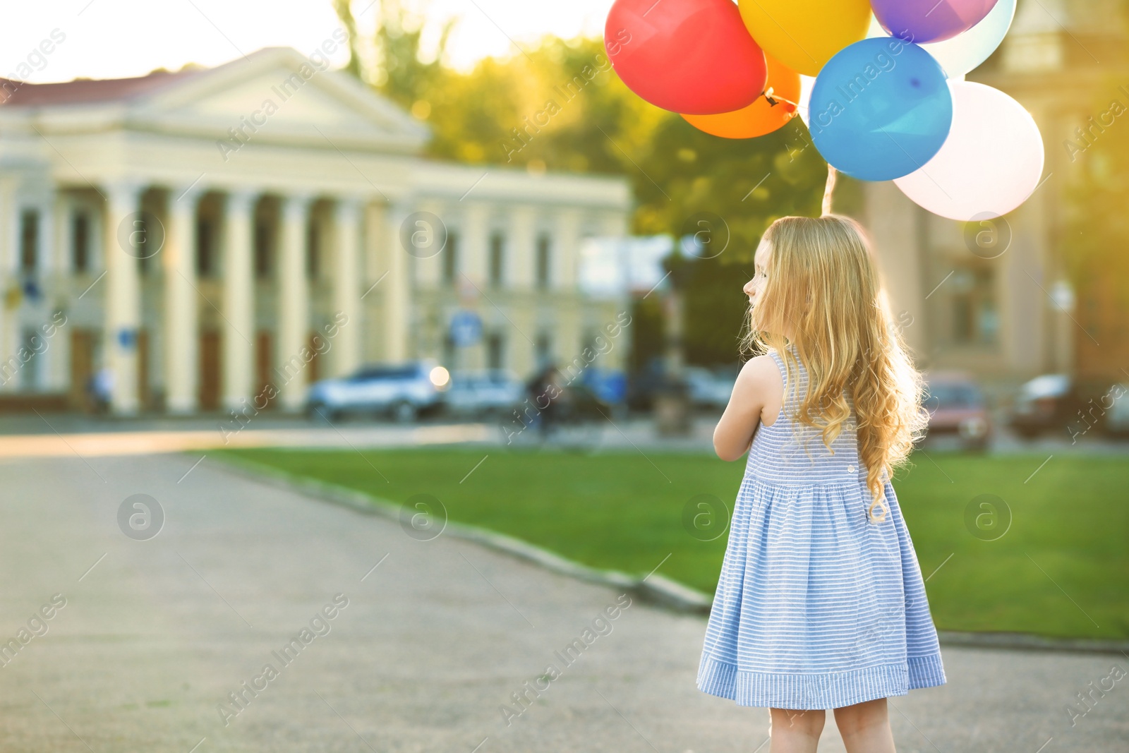 Photo of Little girl with colorful balloons outdoors on sunny day