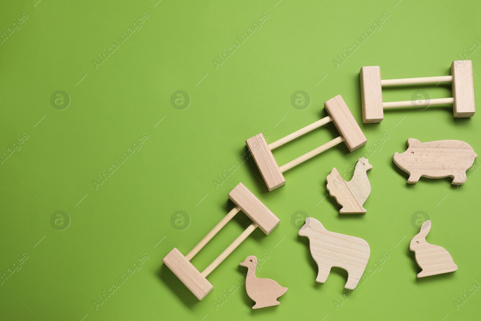 Photo of Wooden animals and fence on green background, flat lay with space for text. Children's toy