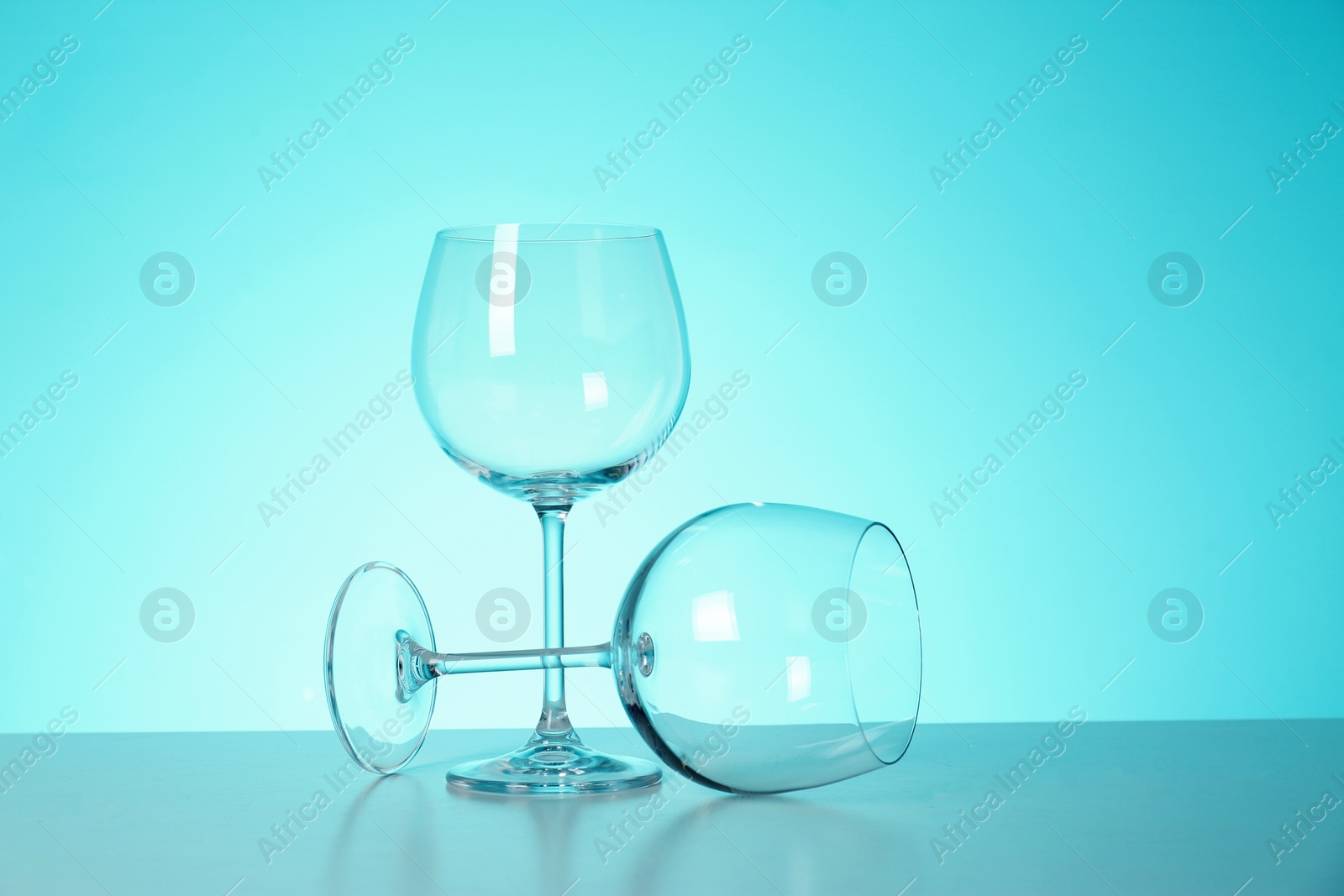 Photo of Clean wine glasses on table against color background