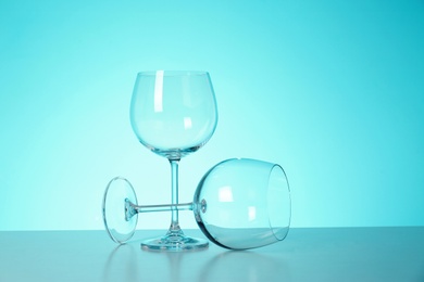 Photo of Clean wine glasses on table against color background