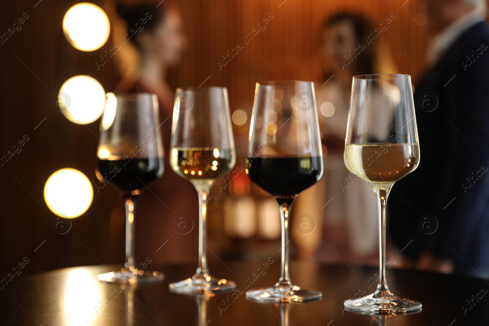 Photo of Glasses of different wines on table against blurred background