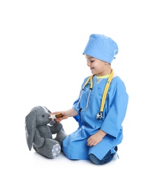 Photo of Cute child playing doctor with stuffed toy on white background